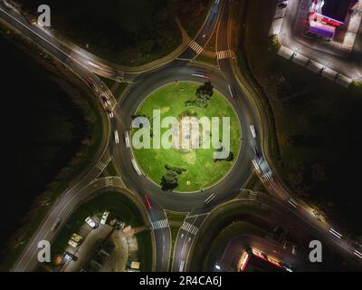Una collezione di automobili sta navigando in un interscambio autostradale tortuoso in prima serata Foto Stock