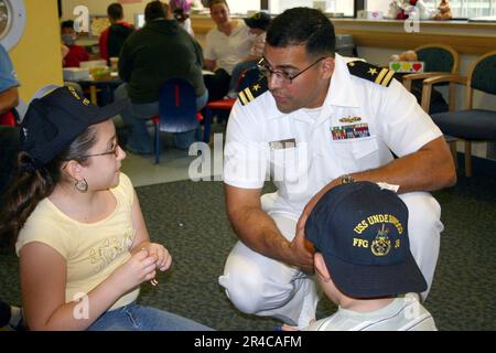 US Navy Lt. Assegnato alla fregata missilistica guidata USS Underwood (FFG 36) parla con due bambini ad un Foto Stock