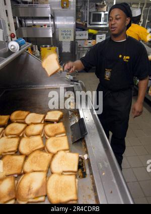 US Navy Culinary Specialist 3rd Class prepara panini al prosciutto e formaggio alla griglia nella principale galea di ufficiali piccoli a bordo della nave d'assalto anfibio USS Iwo Jima (LHD 7). Foto Stock