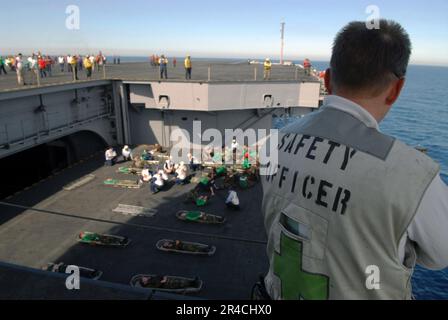 US Navy CMdR. Il responsabile della sicurezza della USS Ronald Reagan (CVN 76), tiene d'occhio i membri del team medico e i partecipanti alle esercitazioni man mano che vengono abbassati sull'ascensore dell'aeromobile della nave. Foto Stock