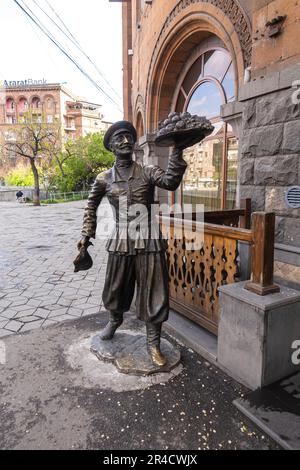 Scultura armena: Uomo che vende melogranadi di frutta. Street art urbana a Erevan Foto Stock