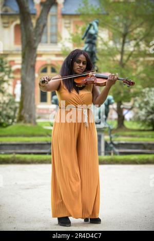 Bella donna nera che suona il violino in un parco a Parigi Foto Stock