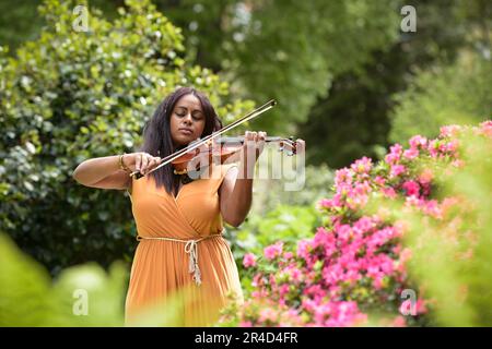 Bella donna nera che suona il violino in un parco a Parigi Foto Stock