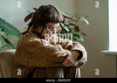 Triste artista millenario ragazza seduta su sedia da finestra sensazione di mancanza di ispirazione Foto Stock