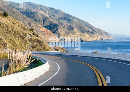 Curva lungo un'autostrada che corre lungo la costa frastagliata della California in una soleggiata giornata autunnale Foto Stock