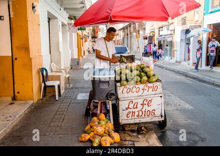 Un uomo vende cocco frio acqua di cocco da un carrello di strada a Cartagena Colombia Foto Stock