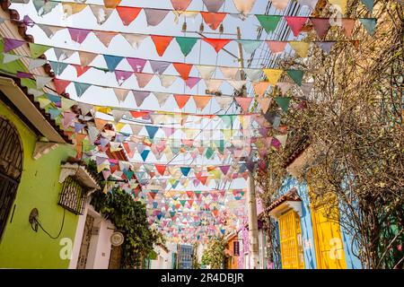 Guardando in alto le bandiere pendenti che si stagliano tra edifici dai colori vivaci di Cartagena Colombia Foto Stock