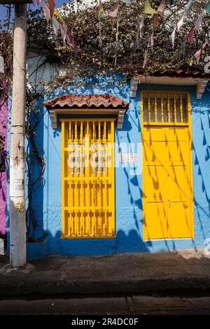 Porta e finestra di colore giallo brillante su una casa blu nel quartiere Barrio Getsemani a Cartagena Colombia Foto Stock