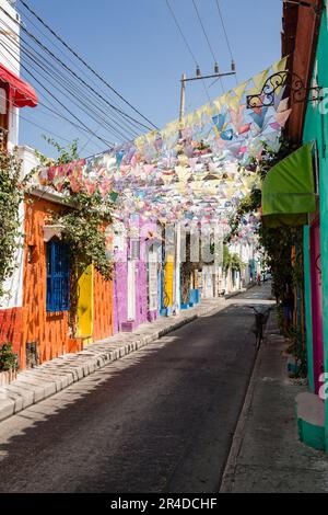 Si affaccia su una strada con bandiere pendenti che si stendono attraverso edifici dai colori vivaci di Cartagena Colombia Foto Stock