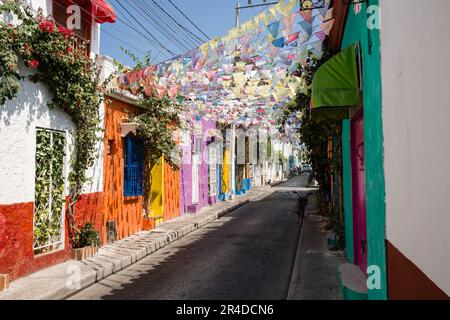 Si affaccia su una strada con bandiere pendenti che si stendono attraverso edifici dai colori vivaci di Cartagena Colombia Foto Stock