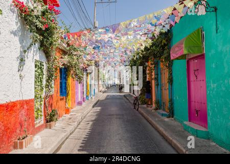 Si affaccia su una strada con bandiere pendenti che si stendono attraverso edifici dai colori vivaci di Cartagena Colombia Foto Stock