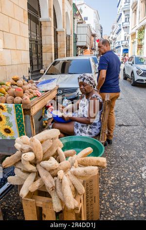 Una donna si siede vicino al suo carrello che vende ortaggi nel centro storico di Cartagena Colombia Foto Stock