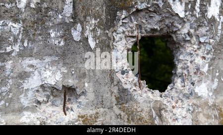 Foto di una parete o recinzione di cemento rotta. Pietra grunge parete dispari con un foro. Danni dovuti a crepe grunge e rottura della parete di cemento. Foto Stock