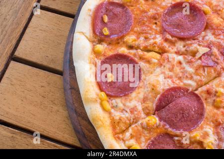 austria, vienna - 8 maggio 2023 pizza con salame, peperoni e mais su tavola di legno Foto Stock
