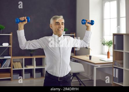 Lavoratore anziano felice che fa l'esercitazione di idoneità durante la giornata di lavoro nel posto di lavoro dell'ufficio Foto Stock