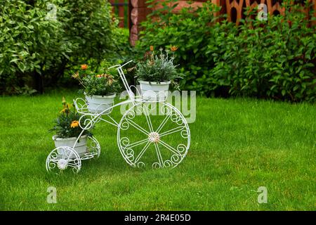 Modello di una vecchia bicicletta dotata di cesto di fiori. Biciclette in giardino Foto Stock