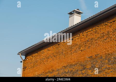 Primo piano camino sul tetto e cielo, muro di mattoni di casa Foto Stock