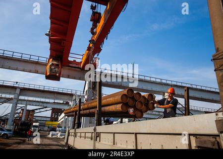 Podolsk, provincia di Mosca - 02 agosto 2021: Tubi di carico dei lavoratori con gru a ponte. Foto Stock