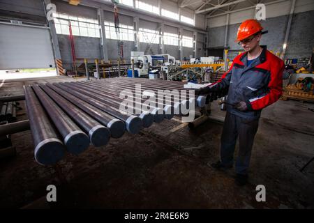 Podolsk, provincia di Mosca - 02 agosto 2021: Giovani woker che controllano i tubi di perforazione pronti per l'uso. Foto Stock