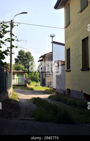Vicolo coperto tra edifici che conduce ad un sentiero vicino ad un campo in una giornata di sole nella campagna italiana Foto Stock