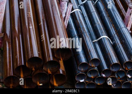 Tubi in acciaio nel magazzino esterno. Tubi bagnati in giorno piovoso Foto Stock