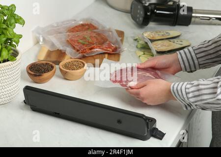 Donna che usa il sigillante per il confezionamento sottovuoto in cucina, closeup. Cucina sous vide Foto Stock