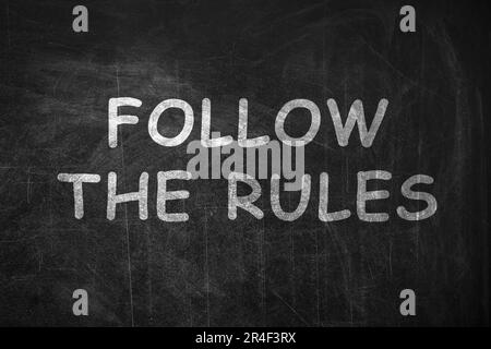 Frase seguire le regole scritte con il gesso sulla lavagna Foto Stock