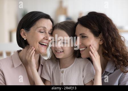 Ragazze e donne allegre di tre generazioni che siedono insieme Foto Stock