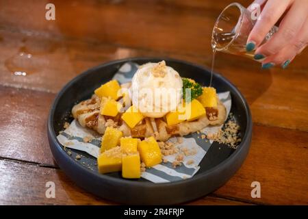 Crostini, ibrido di croissant e waffle al mango, gelato e miele serviti sul piatto Foto Stock