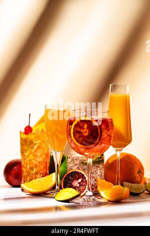 Cocktail alcolici estivi per feste, bevande rinfrescanti con spumante, champagne, gin e rum. Sfondo beige, luce intensa, motivo d'ombra Foto Stock