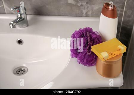 Soffio doccia viola e prodotti cosmetici sul lavandino in bagno, spazio per il testo Foto Stock