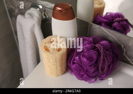 Soffio doccia viola, spugna loofah e bottiglia di gel per il lavaggio del corpo sul lavandino in bagno Foto Stock