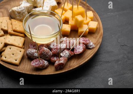 Stuzzichini da dentifricio. Pezzi di salsiccia, formaggio e miele su tavola nera Foto Stock
