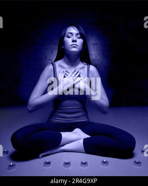 Giovane donna attraente che fa yoga e tenendo la croce nelle sue mani. Colore di 2022 anni, molto peri, toed Foto Stock