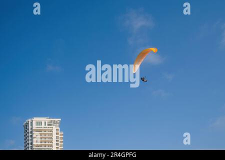 parapendio. sport estremi. La silhouette del parapendio vola nel cielo blu sopra la città Foto Stock