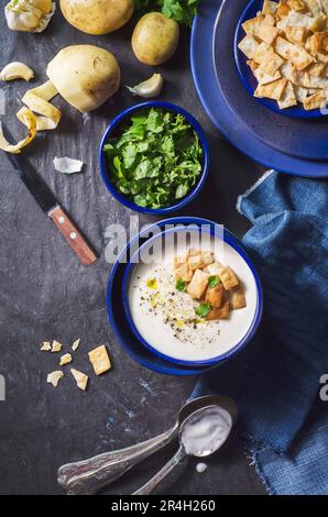 Una ciotola di zuppa di patate con crostini tostati e prezzemolo fresco su fondo di legno scuro. Foto Stock
