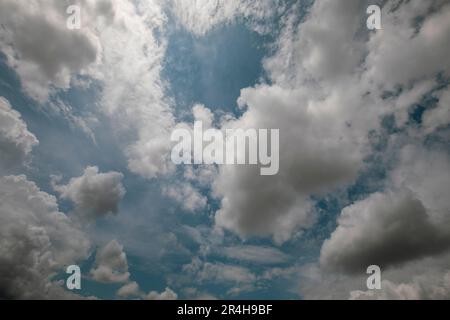 Cielo blu intenso e luminoso con abbondanti nuvole di cirrus bianco e il sole al centro perfetto per sfondi e risorse grafiche Foto Stock