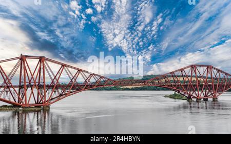 Vista di due carrozze locali ScotRail treno a sbalzo Forth Rail Bridge con acqua calma, Firth of Forth, Scozia, Regno Unito Foto Stock