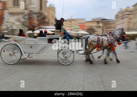 Immagine sfocata del movimento di un carrello trainato da cavalli. Cracovia, Polonia, Europa. Foto Stock