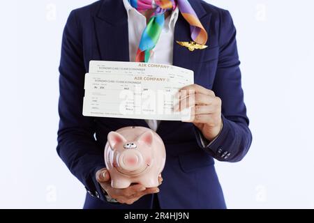 Primo piano su moderna donna di gestione su sfondo bianco in uniforme con biglietti aerei e piggy bank. Foto Stock