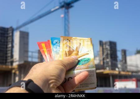 Denaro svizzero sullo sfondo della costruzione, concetto, prezzi degli alloggi, costo dei materiali da costruzione, prestito di alloggi Foto Stock