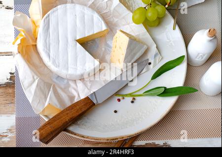 Camembert formaggio morbido sul piatto con uva ed erbe aromatiche Foto Stock