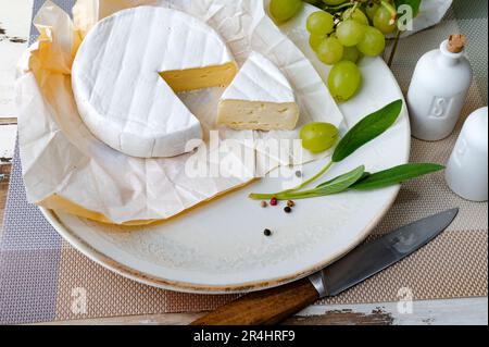 Camembert formaggio morbido sul piatto con uva ed erbe aromatiche Foto Stock