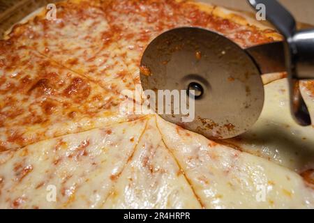 ​​pizza margarita al forno e affettato con affettatrice di pizza Foto Stock