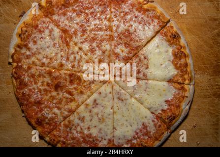 Pizza margherita al forno e tagliata a fette su una tavola di legno Foto Stock