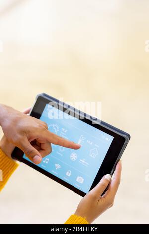 Giovane biraciale che punta all'applicazione sul tablet digitale e sulla donna che controlla la casa intelligente Foto Stock