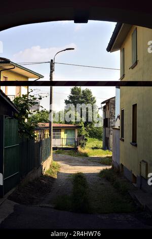 Vicolo coperto tra edifici che conduce ad un sentiero vicino ad un campo in una giornata di sole nella campagna italiana Foto Stock