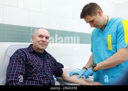 Il medico prende il sangue dall'uomo anziano in clinica Foto Stock