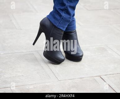 Gamba ragazza con stivali neri sul tacco alto. Stile Street. Foto Stock