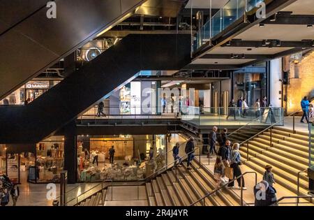 Persone sulle scale e scale mobili presso l'atrio dell'ingresso sud della centrale elettrica di Battersea, oggi una delle principali destinazioni per lo shopping e il tempo libero, Londra, SW11 Foto Stock